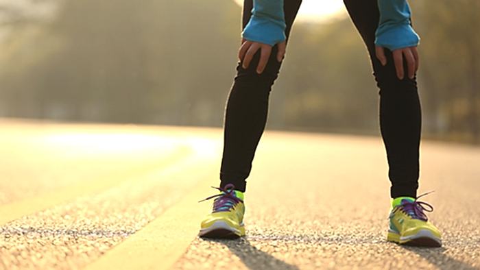 Runner Holding Knees And Taking A Break On Road
