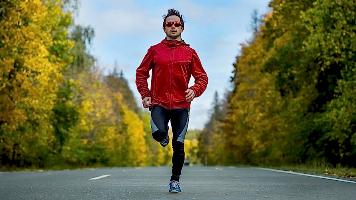 Running Man Running Down A Paved Street Outside On Sunny Day Doing A Fartlek Workout