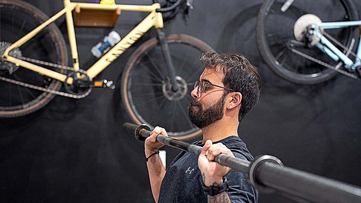 Male Cyclist Doing Barbell Overhead Press For Strength Training